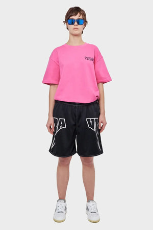 Osoba w różowej koszulce, czarnych sportowych szortach i białych sneakersach, modne okulary lustrzane, styl streetwear