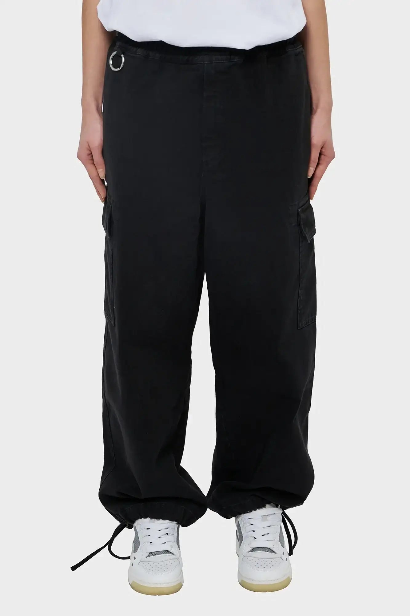 Czarne spodnie cargo typu baggy z kieszeniami, sznurkami przy nogawkach, na modelu