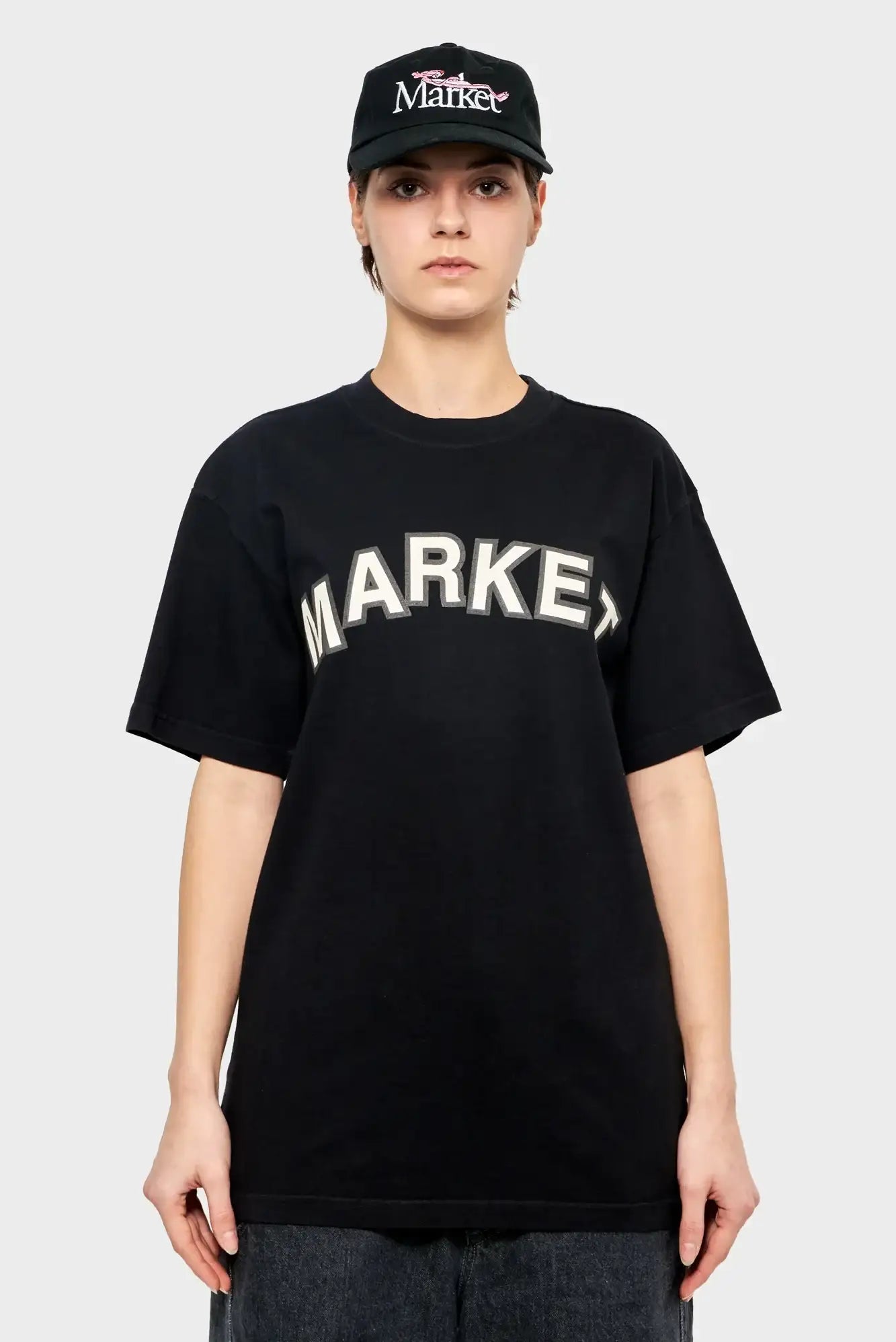 Osoba w czarnej koszulce z napisem MARKET i czapce z daszkiem, styl streetwear