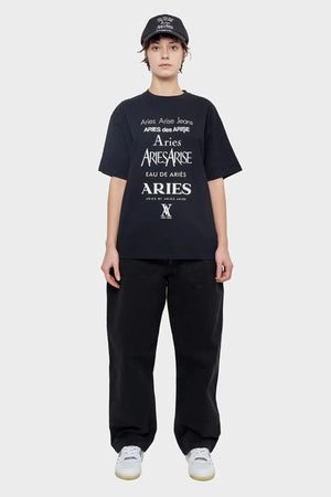 Modelka w czarnej czapce, t-shircie Aries z białym nadrukiem i czarnych spodniach, styl streetwear