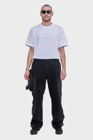 Mężczyzna w białej koszulce z logo i czarnych spodniach polarowych, styl streetwear