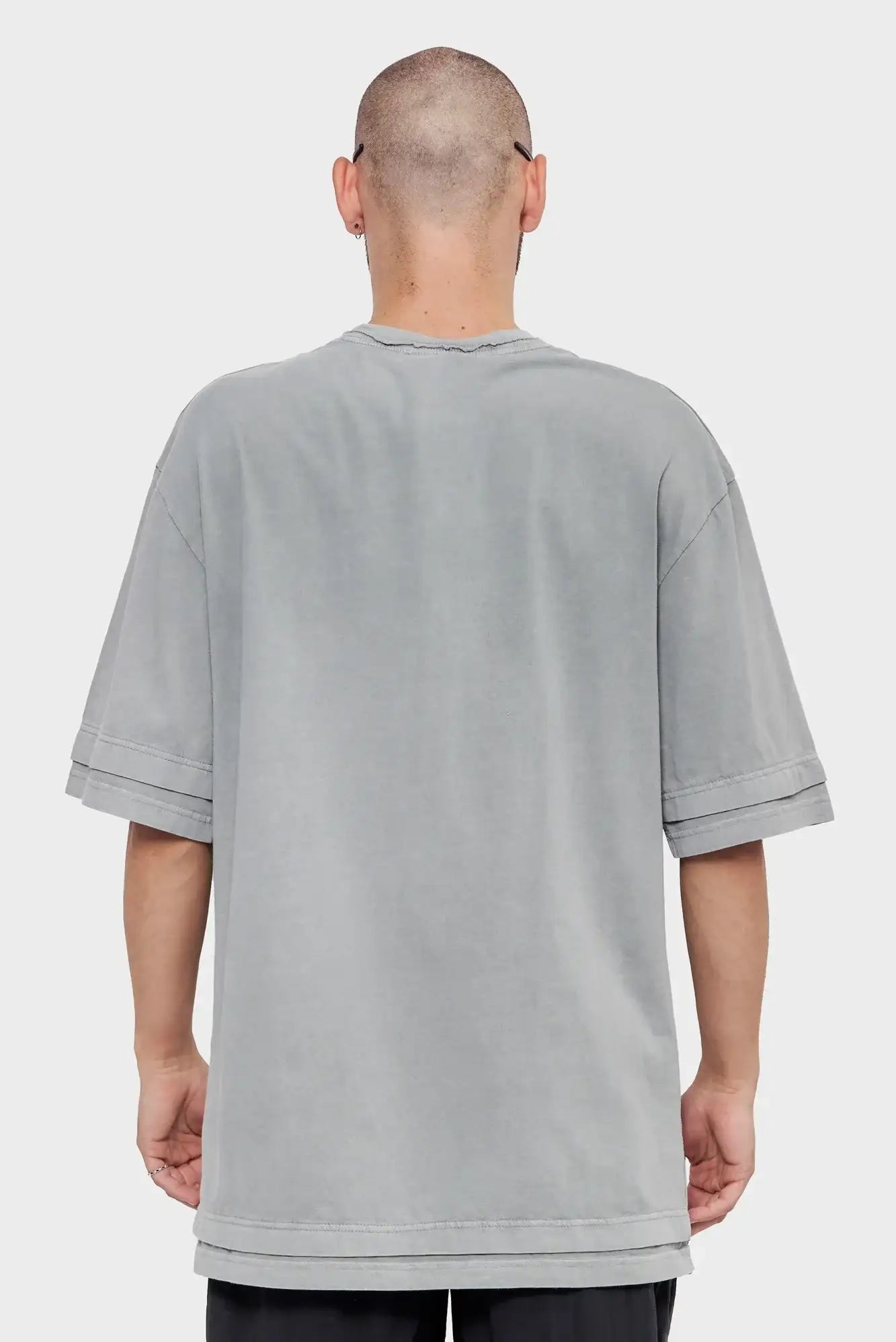 Mężczyzna w oversize szarej koszulce z krótkim rękawem, widok od tyłu, moda streetwear