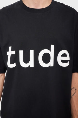 Czarna koszulka z białym napisem "tude", minimalistyczny styl streetwear