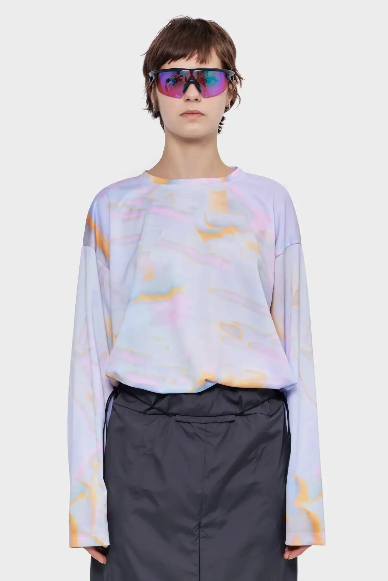 Osoba w okularach przeciwsłonecznych, luźna bluza pastelowa tie-dye, ciemna spódnica, styl streetwear