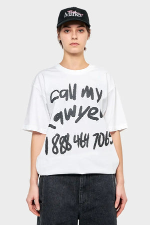Osoba w białej koszulce z napisem 'call my lawyer' i czarnej czapce z daszkiem, styl streetwear
