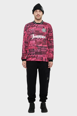 Mężczyzna w czarnej czapce i różowej bluzie z nadrukami, czarne spodnie cargo, styl streetwear