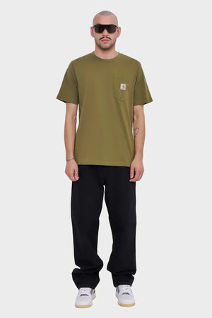 Mężczyzna w oliwkowym t-shircie z kieszonką, czarnych spodniach i białych sneakersach na szarym tle.