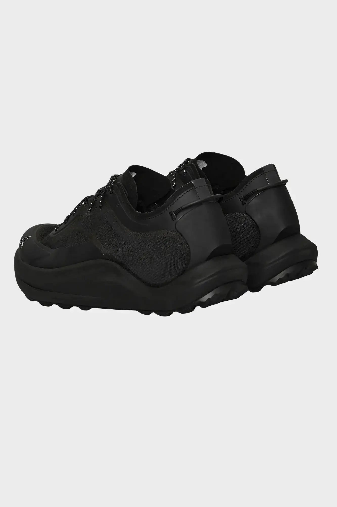 Czarne sneakersy z tkaniny i skóry z dynamiczną podeszwą, widok z tyłu na neutralnym tle