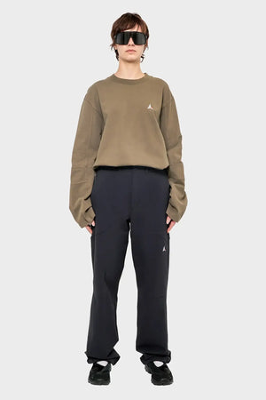 Modelka w dużych okularach, luźna beżowa bluza, czarne spodnie, styl streetwear