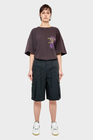 Kobieta w oversize'owej koszulce z nadrukiem i czarnych szortach cargo, sneakersy, styl streetwear