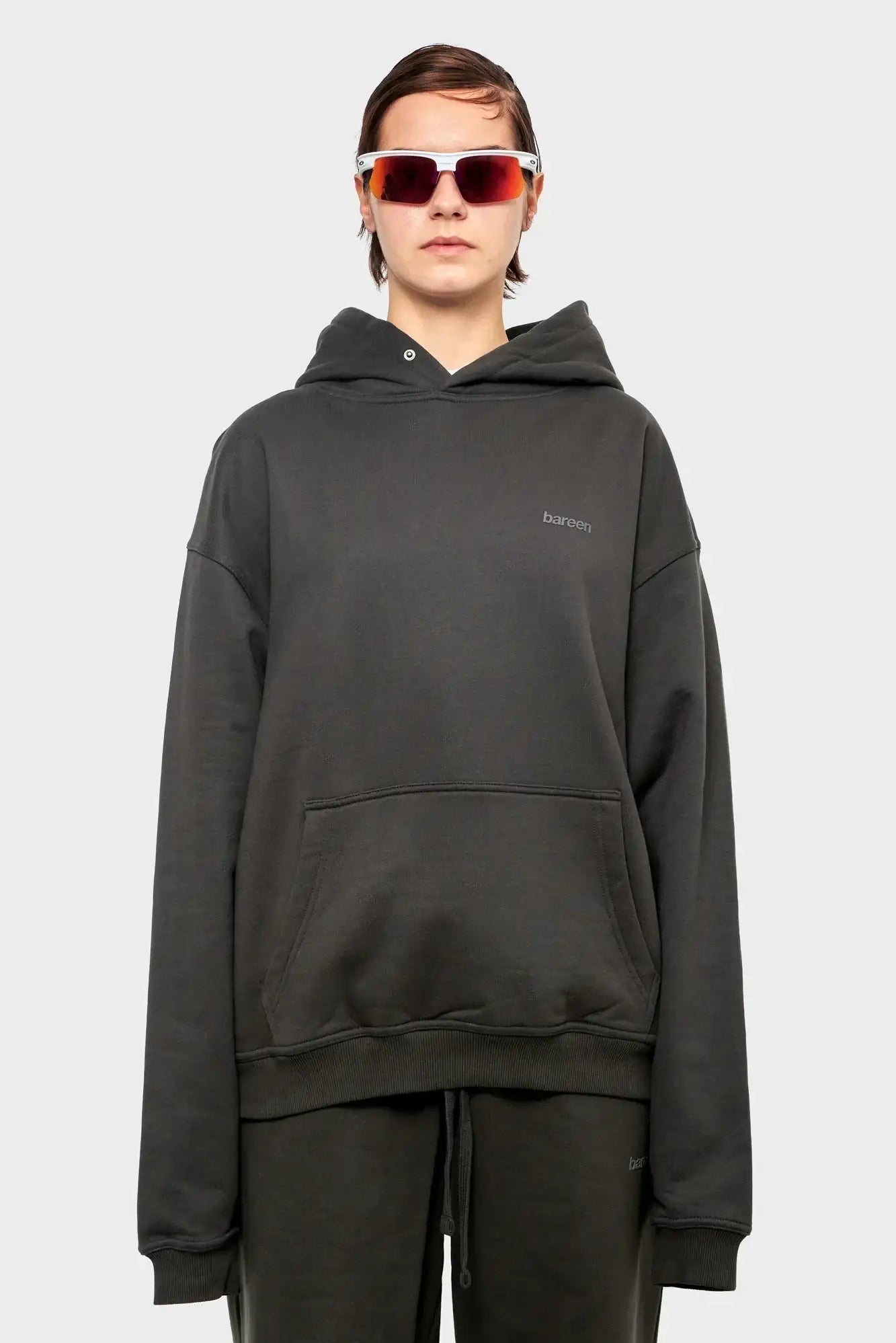 Osoba w ciemnej bluzy z kapturem i okularach sportowych, minimalistyczna moda streetwear