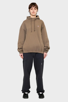 Osoba w beżowej bluzie z kapturem i czarnych spodniach, minimalistyczna stylizacja streetwear