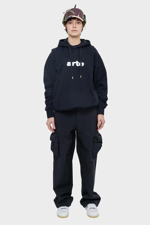 Modelka w czarnej bluzie Arte, bojówki cargo, buty sportowe, czapka z daszkiem, streetwear
