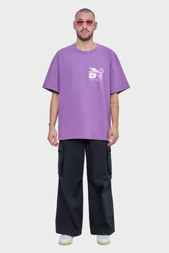 Mężczyzna w fioletowej koszulce oversize, czarnych bojówkach i białych sneakersach, modny streetwear.