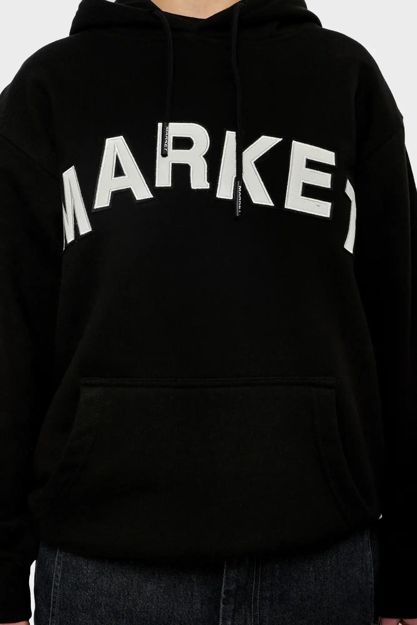 Czarna bluza z kapturem, duży biały napis MARKET na przodzie, kieszeń kangurka, styl streetwear