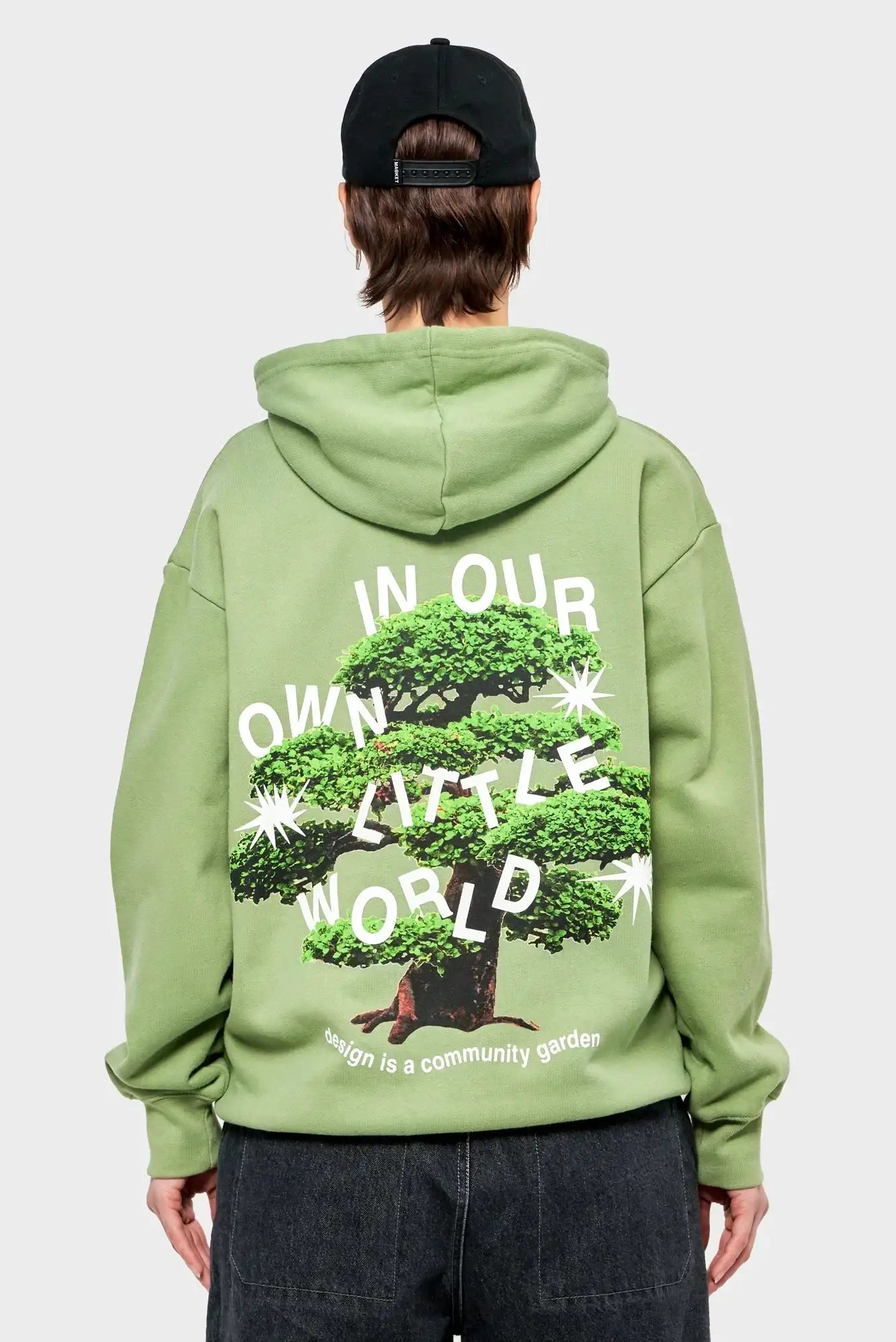 Zielona bluza z kapturem, nadruk drzewo bonsai i napis IN OUR OWN LITTLE WORLD, moda streetwear.