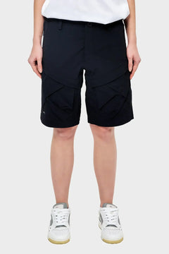 Czarne szorty cargo z dużymi kieszeniami, styl streetwear, na modelce w białych sneakersach