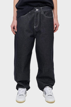 Czarne jeansy typu loose fit z białymi szwami, styl streetwear, sportowe sneakersy