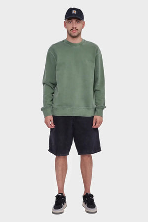 Mężczyzna w zielonej bluzie, czarnych szortach i czapce z daszkiem, styl streetwear