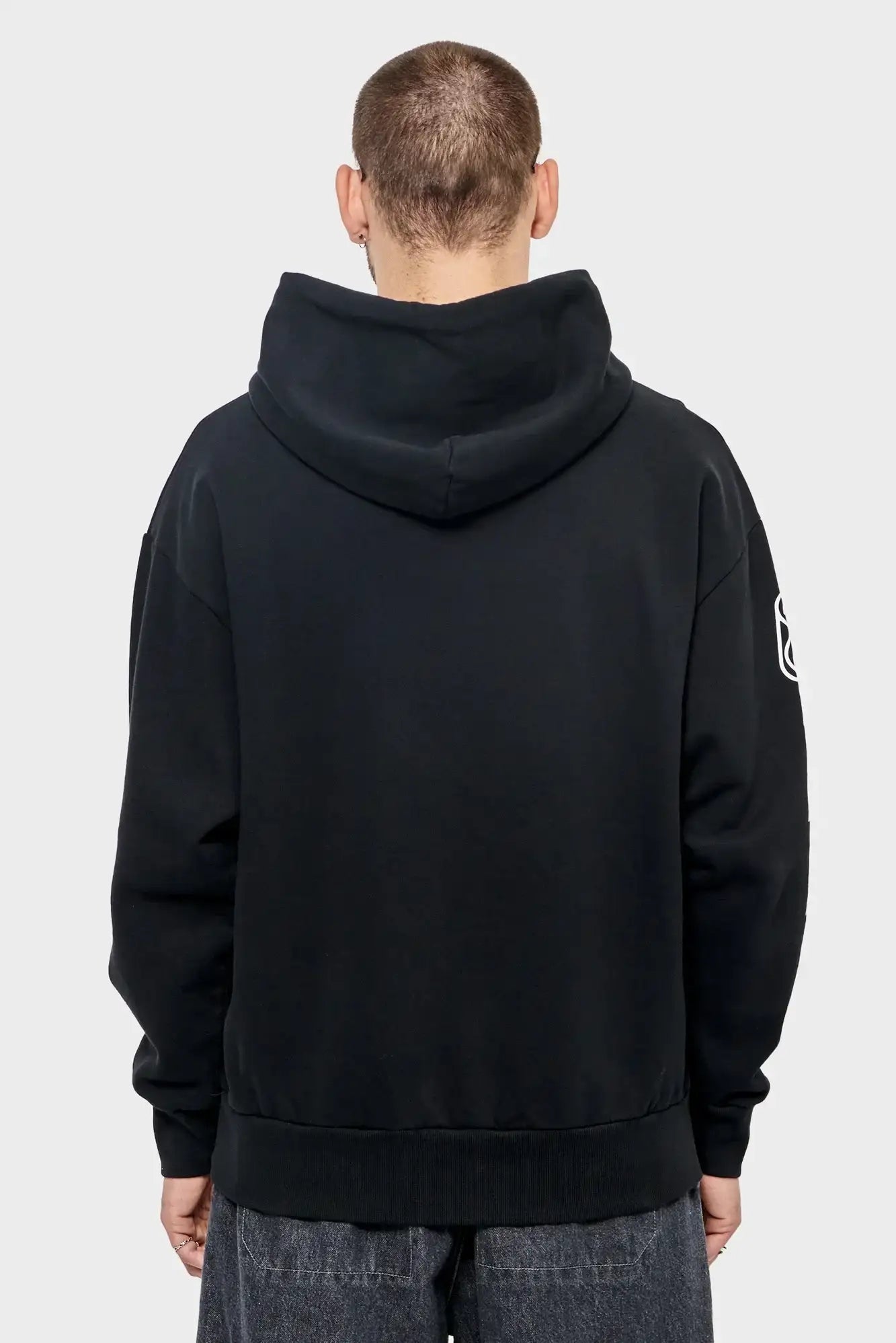Mężczyzna w czarnej bluzie z kapturem, tył, minimalistyczny styl streetwear
