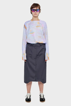 Osoba w okularach sportowych, pastelowej bluzie tie-dye i czarnej spódnicy, styl streetwear.