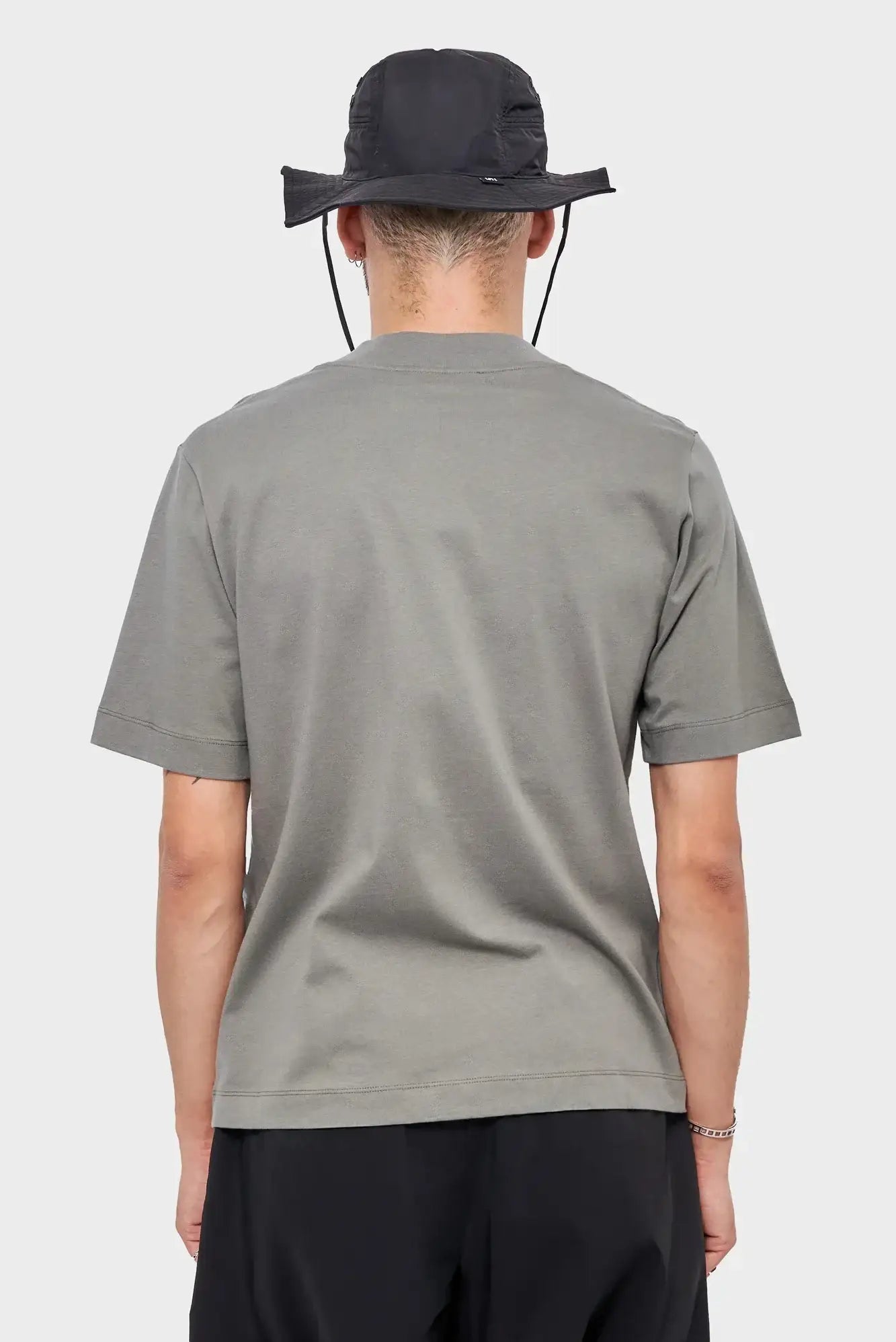 Mężczyzna w szarej koszulce i czarnym kapeluszu, widok od tyłu, moda streetwear