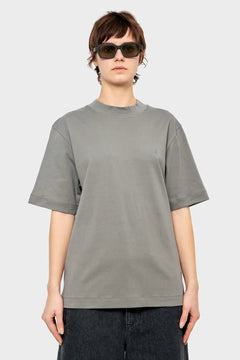 Osoba w szarej oversize koszulce, czarnych okularach przeciwsłonecznych, styl streetwear