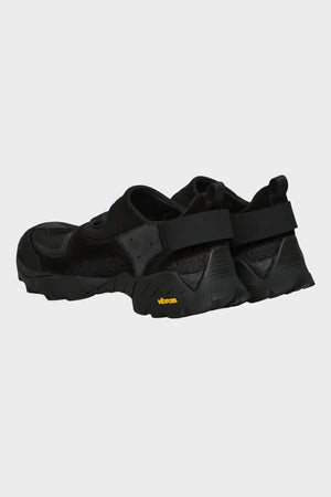 Czarne sportowe buty z grubą podeszwą Vibram, widok z tyłu na białym tle