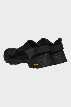 Czarne sportowe buty z grubą podeszwą Vibram, widok z tyłu na białym tle