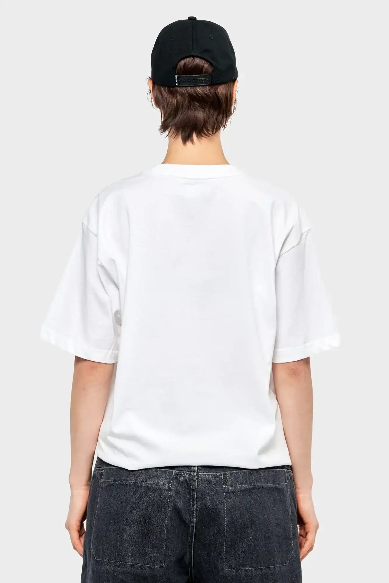 Osoba w białym t-shircie i czarnej czapce z daszkiem, widok od tyłu, styl streetwear