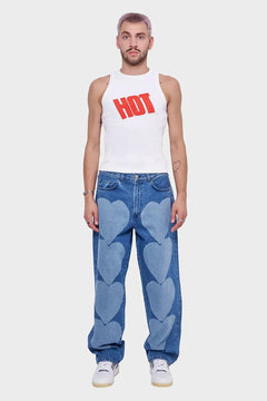 Mężczyzna w białym topie z napisem HOT i niebieskich jeansach z nadrukiem serc, styl streetwear