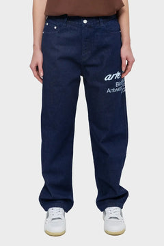 Granatowe jeansy z białym napisem, luźny krój, sportowe buty, styl streetwear