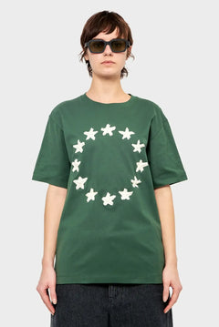 Osoba w zielonej koszulce z białymi gwiazdami w okręgu, modne okulary, styl streetwear