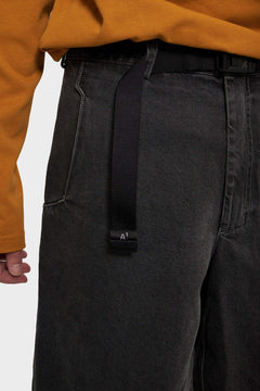 Czarne jeansy z paskiem, detal przy kieszeni, pomarańczowa bluza, moda streetwear