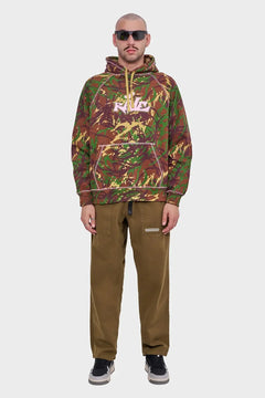 Mężczyzna w bluzie z kapturem w militarny wzór, brązowe spodnie, sneakersy, okulary przeciwsłoneczne