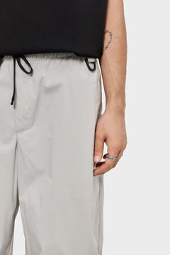 Męskie spodnie z jasnej tkaniny, sznurek w pasie, minimalistyczny styl streetwear