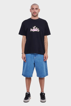 Mężczyzna w czarnej koszulce z napisem RAVE, jeansowe szorty i sneakersy, moda streetwear
