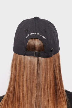 Czarna czapka z daszkiem z napisem FUNDAMENTAL UNIT na tyle, długie proste włosy, styl streetwear