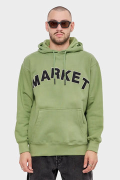 Mężczyzna w zielonej bluzie z kapturem MARKET, czarne okulary, minimalistyczna stylizacja streetwear