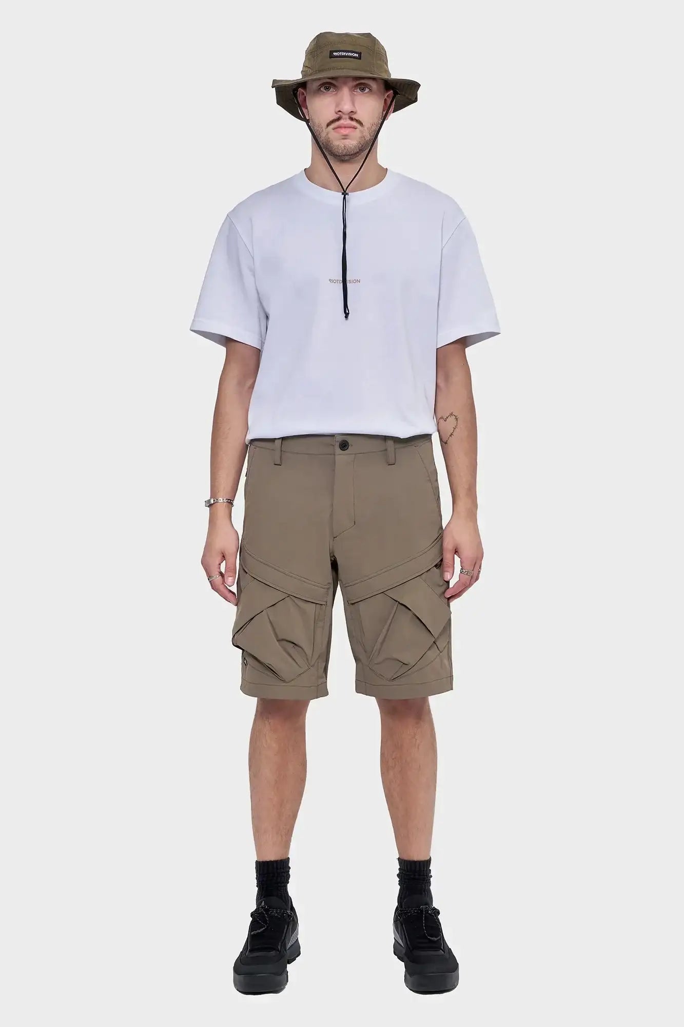 Mężczyzna w białym t-shircie, khaki szortach cargo i oliwkowym kapeluszu typu bucket hat