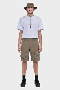 Mężczyzna w białym t-shircie, khaki szortach cargo i oliwkowym kapeluszu typu bucket hat