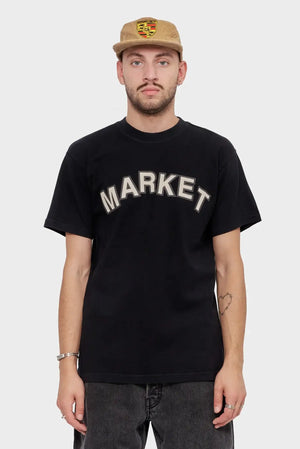 Mężczyzna w czarnej koszulce z napisem MARKET i beżowej czapce z naszywką, moda streetwear