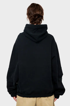 Czarna bluza z kapturem oversize, widok od tyłu, beżowe spodnie, styl streetwear