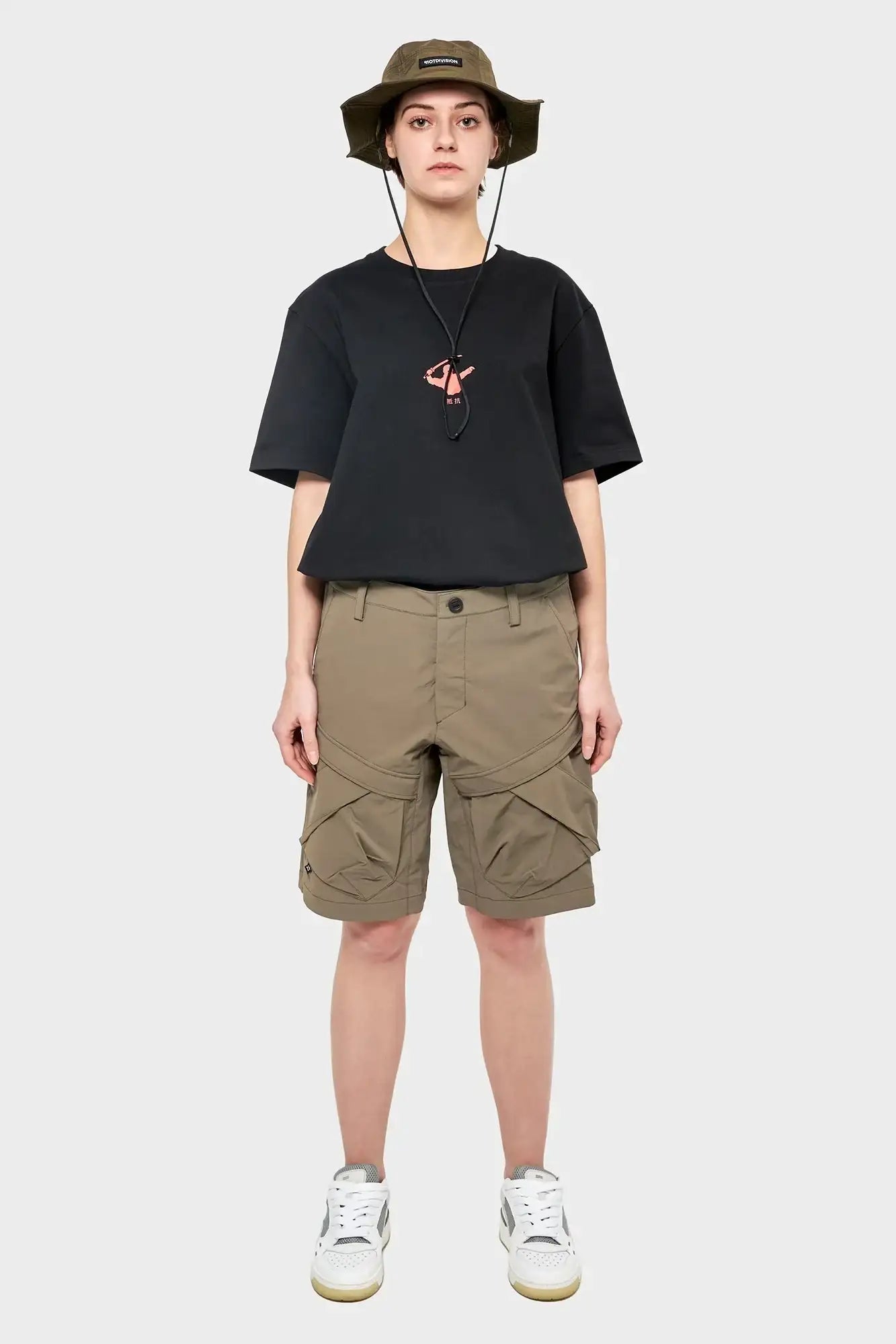 Modelka w czarnym t-shircie, oliwkowych szortach cargo i kapeluszu bucket