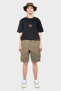 Modelka w czarnym t-shircie, oliwkowych szortach cargo i kapeluszu bucket
