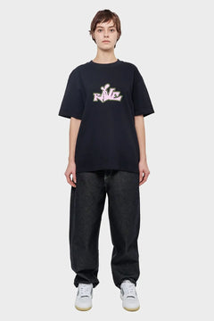 Osoba w czarnej koszulce z napisem RAVE, luźne jeansy, białe sneakersy, styl streetwear