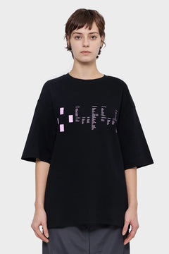 Kobieta w czarnej oversize koszulce z różowym nadrukiem, moda streetwear