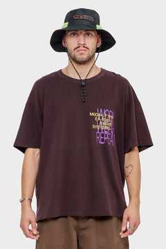 Mężczyzna w brązowej koszulce z nadrukiem MOD44, bucket hat, styl streetwear.