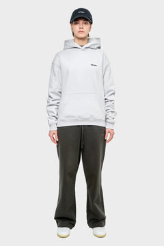Modelka w jasnej bluzie z kapturem, czarnej czapce i ciemnych spodniach dresowych, look streetwear