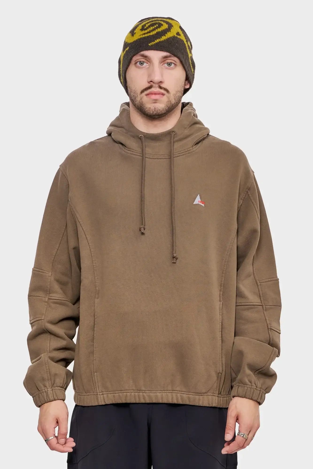 Mężczyzna w brązowej bluzie z kapturem i beżowo-żółtej czapce, moda streetwear